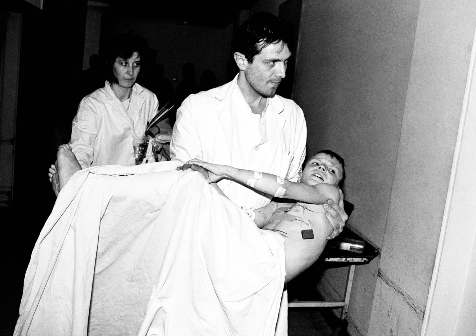 A young doctor carries a wounded boy through a hospital corridor, Sarajevo, 1994